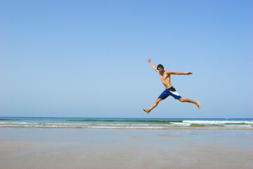 Picture of a young man jumping on the beach