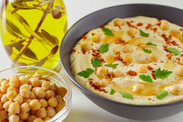 Hummus with chickpeas and olive oil in a dark bowl, selective focus