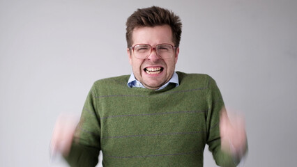 European young man is dissatisfied with the result, he gets angry and contorts a grimace of...