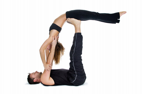 Male and female gymnasts practicing a complex double yoga pose.