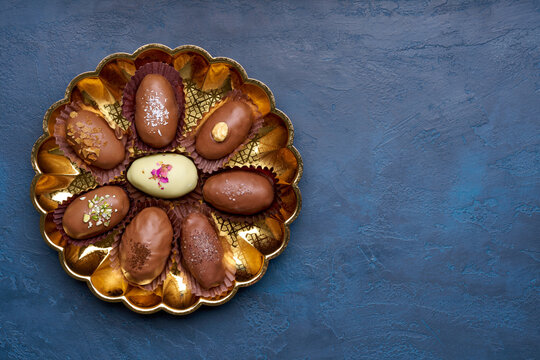 Chocolate covered dates stuffed with various fillings  on blue background   . Top view, copy space