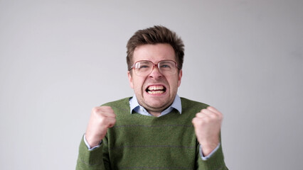 European young man is dissatisfied with the result, he gets angry and contorts a grimace of...