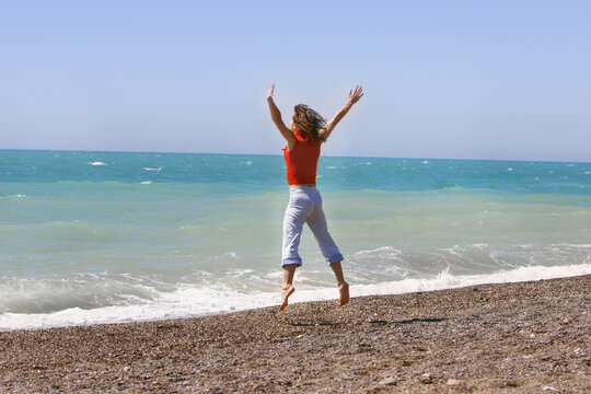 Young woman jumping happily on the beach