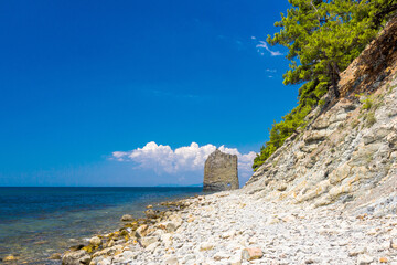 Seascape, pebble beach and cliff, flat stone rock, clear day