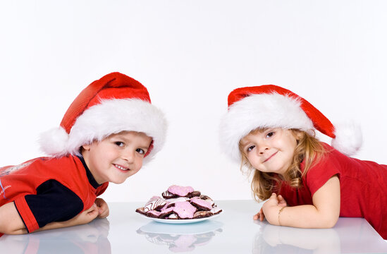 Happy kids with christmas cookies and santa hats  on white background