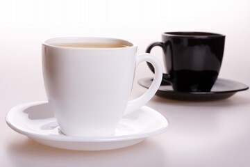white and black cup of tea standing on the table