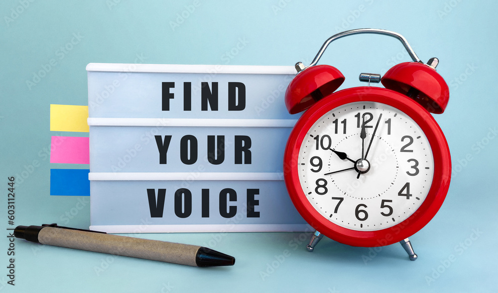 Poster text find your voice written on the lightbox with alarm clock and colorfull stickers on blue backgro