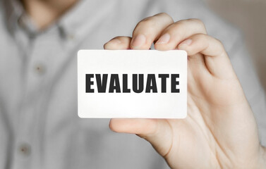 Card with text EVALUATE in a man's hand