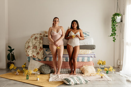 wide shot of two women in front of a pile of mattresses