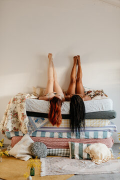 two women lying on a pile of mattresses