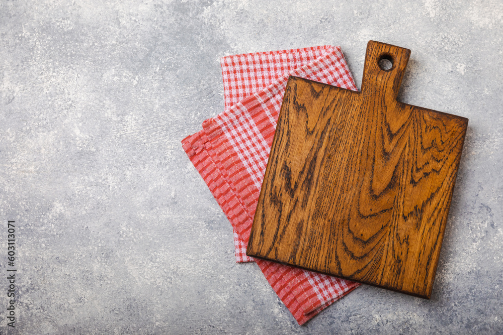 Wall mural Cutting board over kitchen towel on gray kitchen table texture background. Recipe. Kitchenware. Empty modern wooden cutting board. Menu. MOCKUP. Place for text. Place to copy.