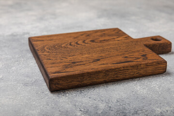 Cutting board on gray kitchen table texture background. Recipe. Kitchenware. Empty modern wooden cutting board. MOCKUP. Place for text. Place to copy.