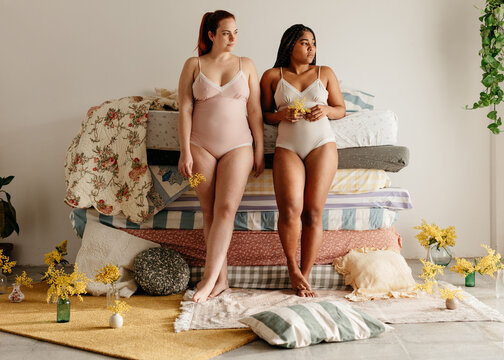 two girls standing in front of a pile of mattresses