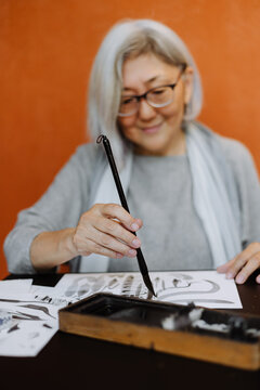 focused woman creating calligraphy works