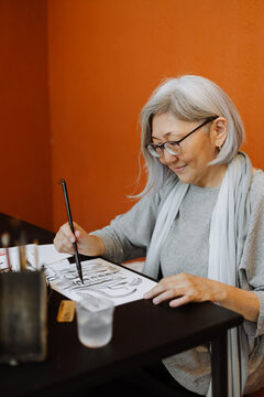 Mature woman practicing calligraphy in workshop