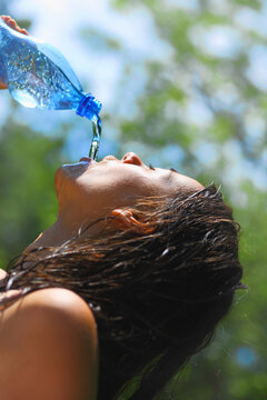 Young woman drinking water outdoors. She has a thirst.  Side view