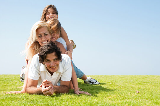 Family piled up on meadow and smiling at camera