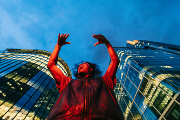 Dancing young man under skyscrapers at night