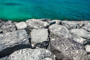 Large boulders stones, breakwaters on the sea with turquoise water