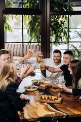Happy group of friends drinking and clinking with beer and cocktails at brewery bar restaurant. Beverage life style concept with guys and girls having fun together
