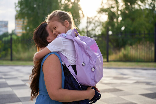 Girl hugging her mother in front of school - Powered by Adobe