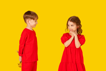 A little gentleman. Funny kids, happy little boy giving a cute girl bouquet of yellow spring flowers. Series in studio. Mother's Day, 8 March, the birthday, the International Women's Day