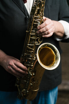 Crop man playing saxophone on street