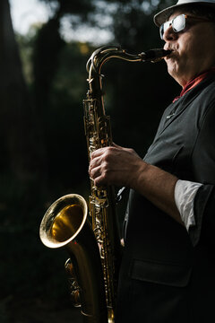 Man playing saxophone on street during sunny day