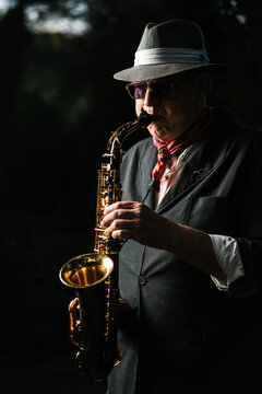 Adult man in hat playing saxophone on street