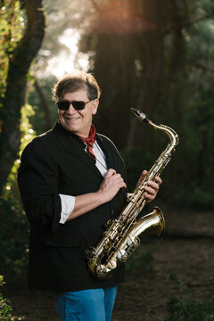 Happy man with saxophone in forest during daytime