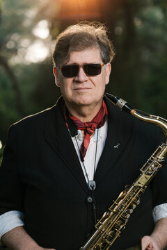 Man in sunglasses playing saxophone in park