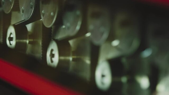 The glass enters the machine on rollers and undergoes a hardening process. The main gears that drive the machine rotate in the frame.