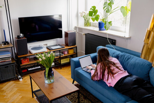 A woman is engaged in online shopping at home on the couch. 