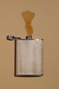 hip flask spilling liquor on a brown surface