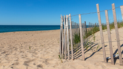 sand dunes and fence with ocean background