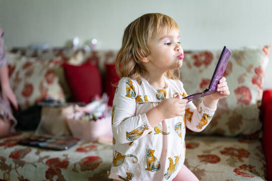 happy child looks in the mirror after applying makeup