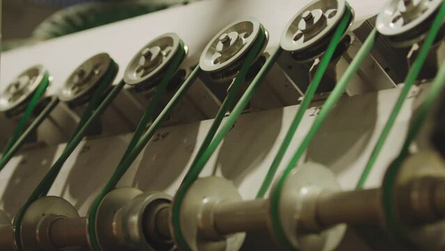 The glass enters the machine on rollers and undergoes a hardening process. The main gears that drive the machine rotate in the frame.