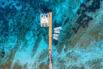Aerial view of boats and luxure yachts in dock at sunset in summer in Sardinia, Italy. Colorful landscape with sailboats and motorboats in sea bay, jatty, clear blue sea. Top view of harbor. Travel