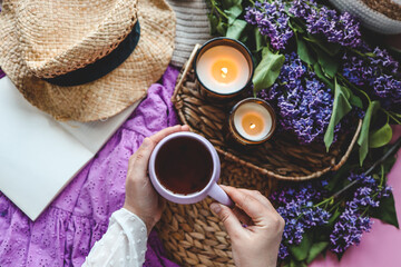 A cup of tea in hands on a background of lilac, top view, aesthetic photo
