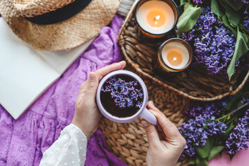 A cup of tea in hands on a background of lilac, top view, aesthetic photo