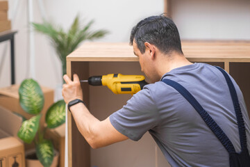 close up Furniture installation skilled handyman attaching door fasteners to cabinet made of...