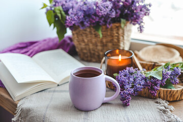 Cup of tea, straw hat, open book and lilac basket, spring still life