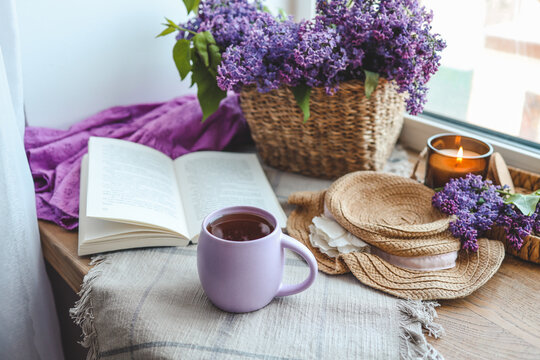 Cup of tea, straw hat, open book and lilac basket, spring still life