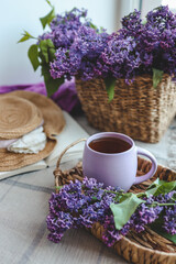 Cup of tea, straw hat and lilac basket, spring still life