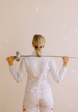  young woman with white fencing uniform from behind 
