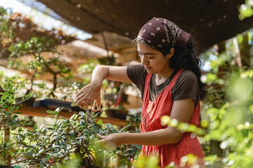 Portrait of a woman cutting the leaves of a plant. 