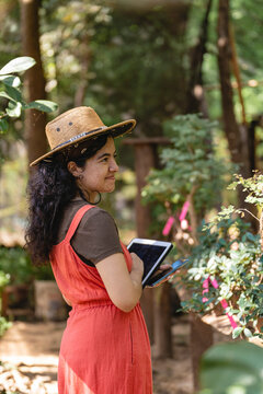 Woman In Hat Taking Inventory In Garden With Tablet 