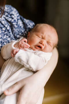 Grumpy newborn baby in mothers arms