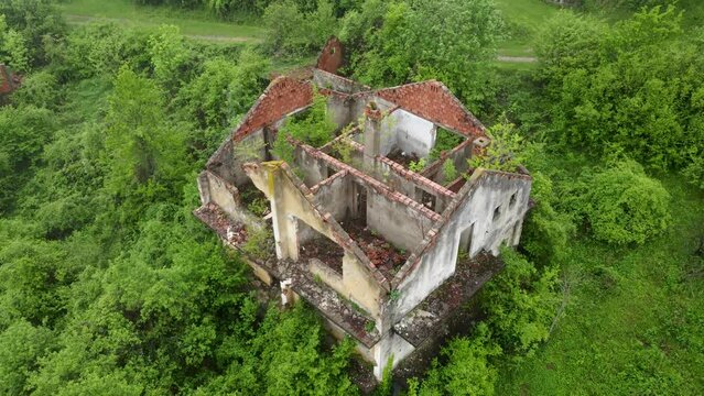 Aerial drone view of ruined and damaged house in village as war aftermath in Bosnia and Herzegovina. Houses destroyed and burned by artillery during the war . Abandoned buildings. Houses in ruins. 