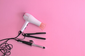 set para arrumar cabelo prancha, secador, boblis em fundo cor de rosa 